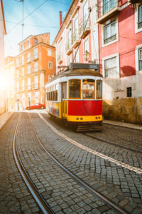 Touristic vintage red tram in a Lisbon street on sunny afternoon, narrow streets, cobblestones winding road, vacation in Lisbon Touristic vintage red tram in a Lisbon street on sunny afternoon, narrow streets, cobblestones winding road, vacation in Lisbon